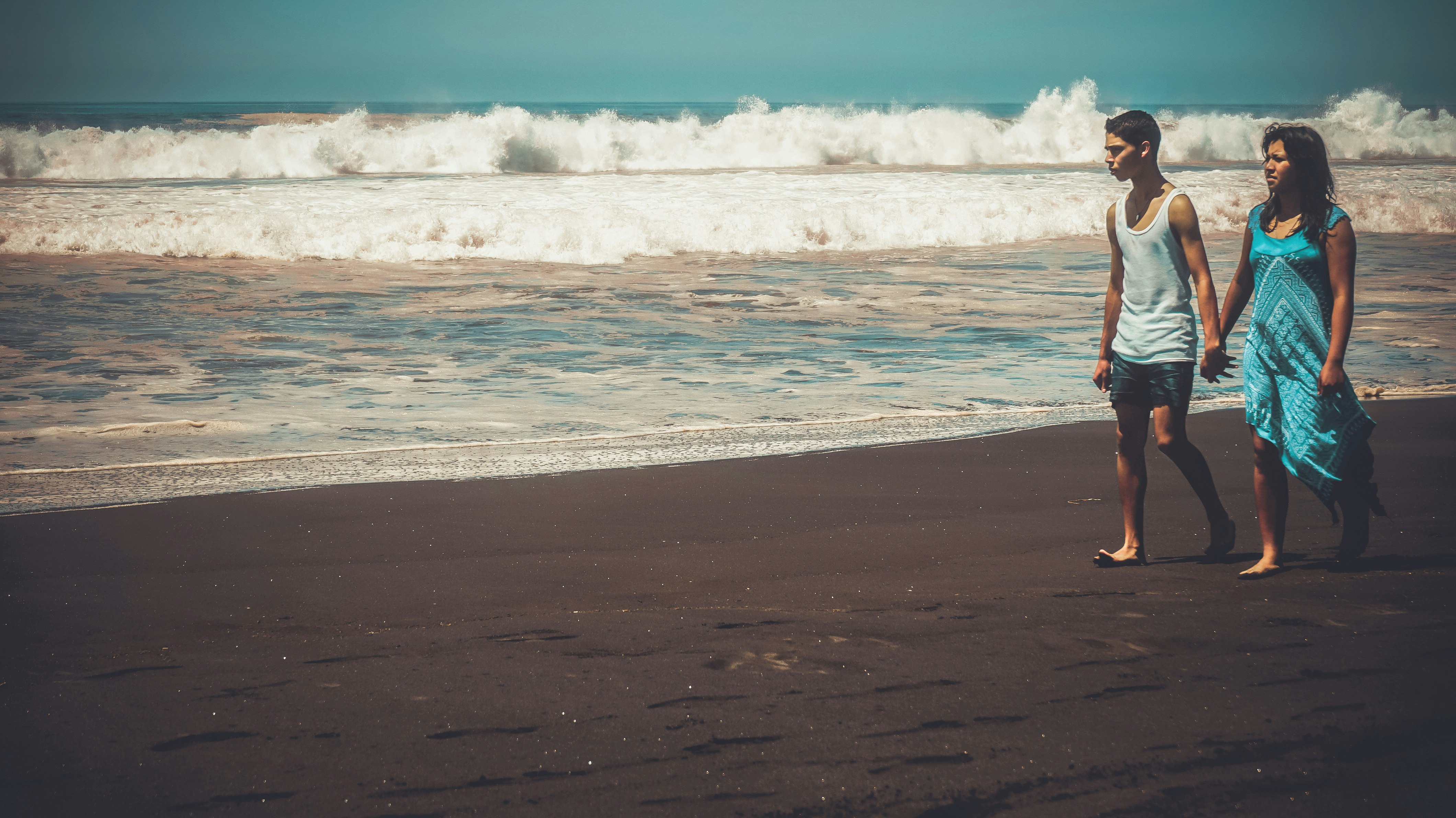 woman in red dress walking on beach during daytime